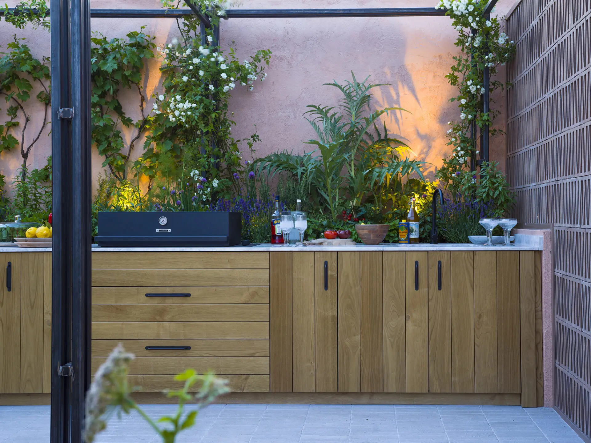 Bespoke Outdoor Kitchen Installation Surrounded By Greenery Featuring Solid Timber Cabinetry And Stone Worktop