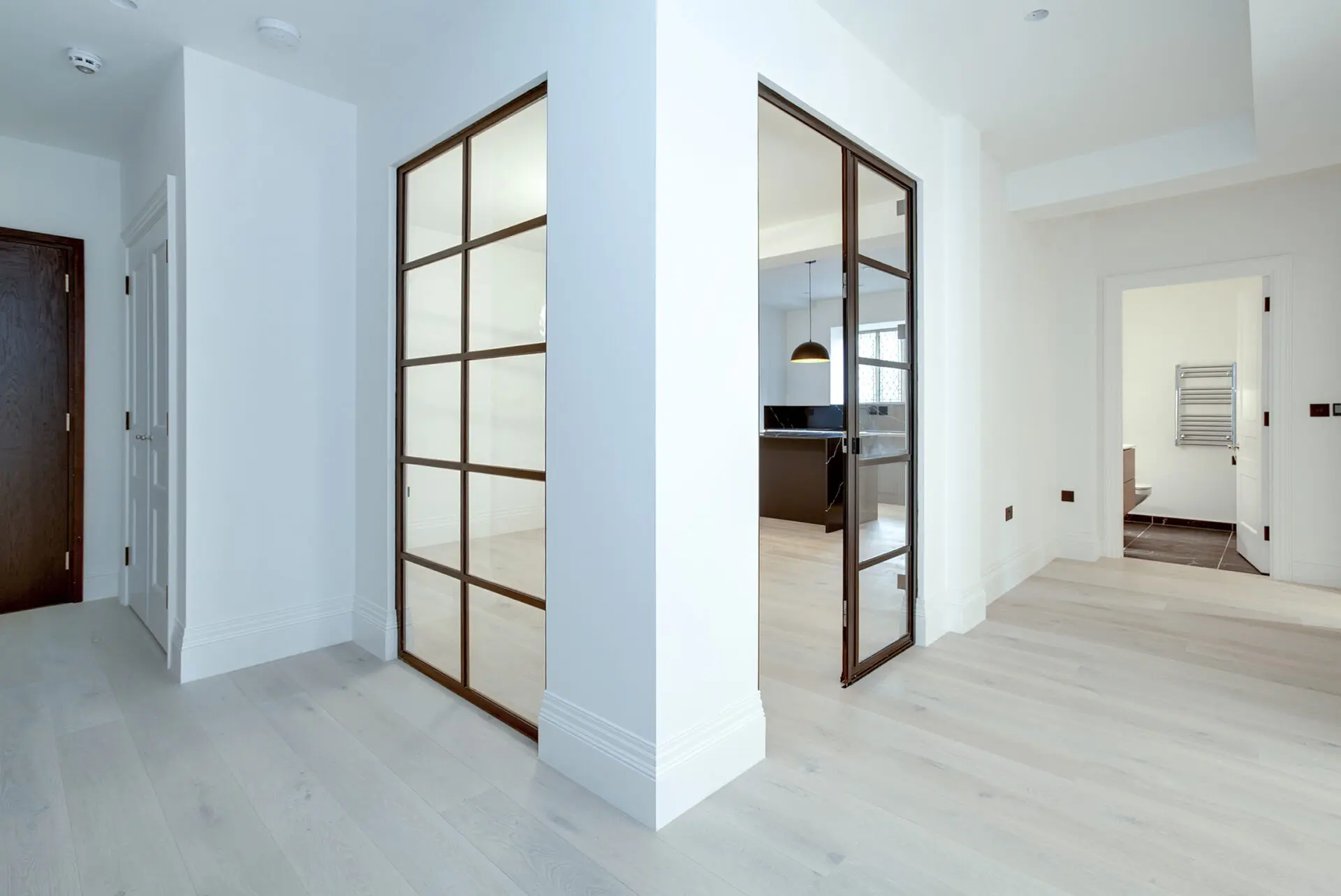 Contemporary Bauhaus Kitchen Featuring Black Framed Glass Partitions And Neutral Toned Cabinetry For A Refined Minimalist Look